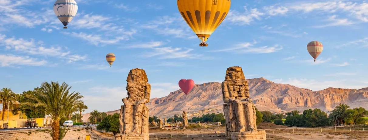 colosses memnon entouré de montgolfiere sous un ciel bleu