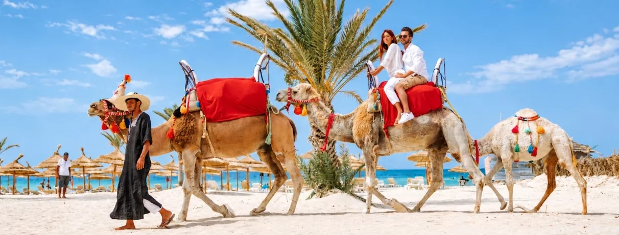 Couple à dos de chameau lors d'une balade sur la plage de sable blanc du Djerba Golf.
