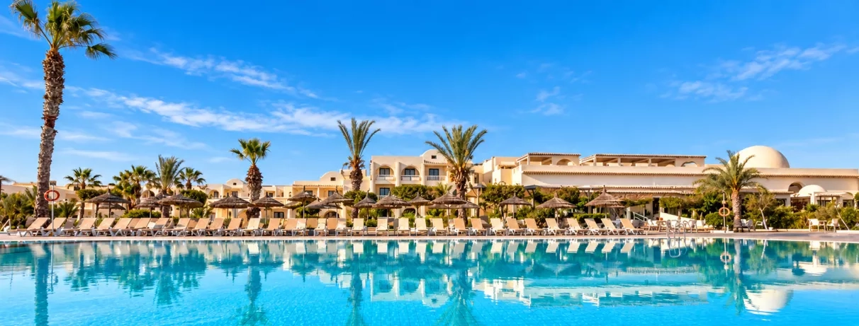 vue de la piscine avec palmiers et façade de l'hôtel du Djerba Aqua Resort à Djerba en Tunisie