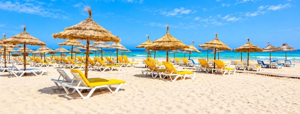 Plage privée avec transats avec parasols et mer turquoise au Djerba Aqua Resort à Djerba en Tunisie