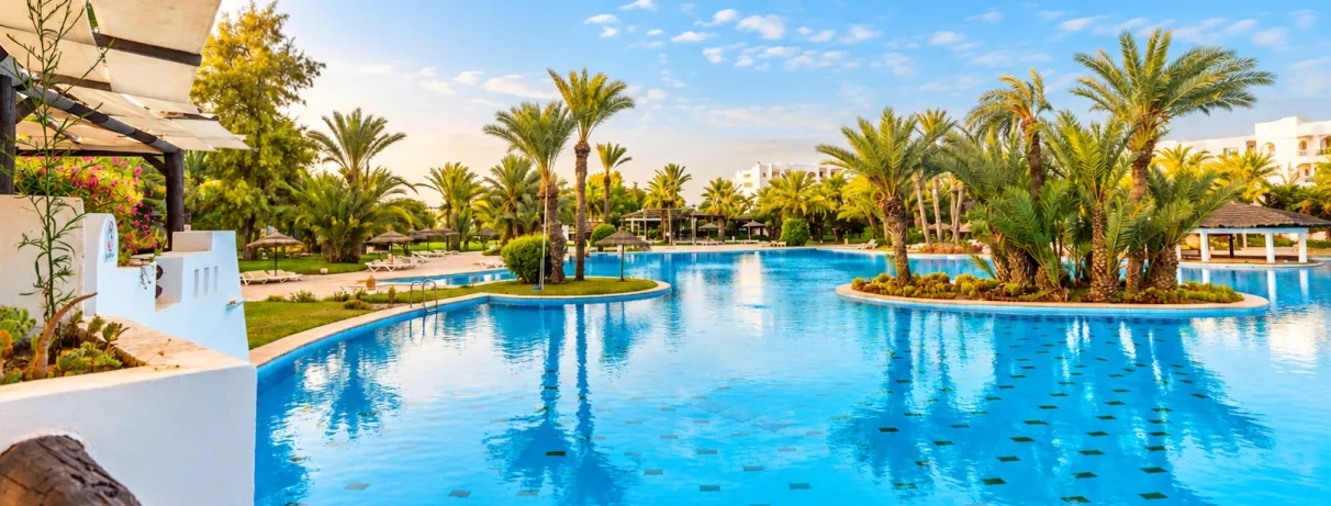 Espace de baignade luxueux avec îlots de palmiers au Djerba Resort, destination de vacances en Tunisie.