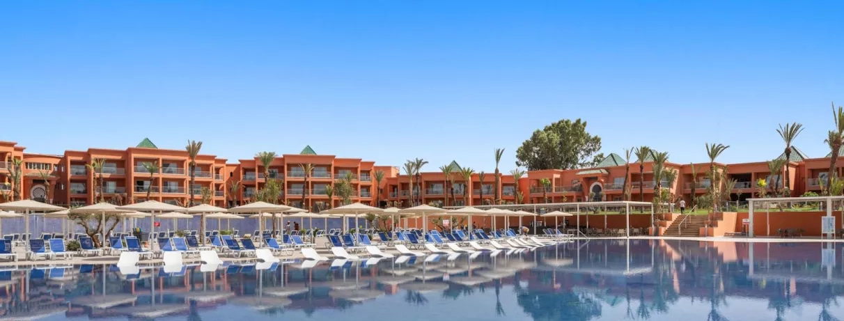 Vue Générale sur la piscine extérieure avec des transats au bord de la piscine et un salon marocain à toit couvert  