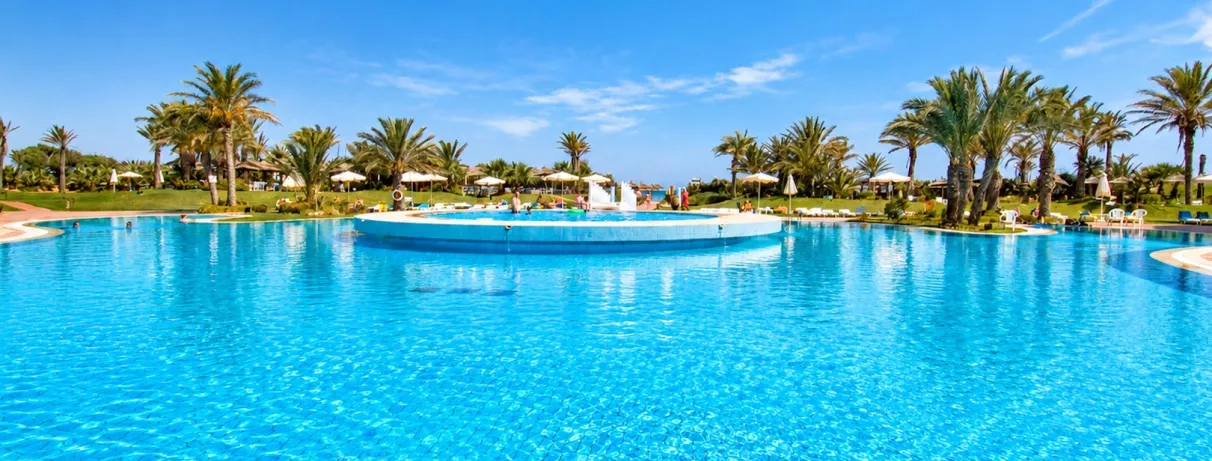 Piscine lagon aux eaux bleues cristallines entourée de palmiers sous un ciel dégagé à Monastir.