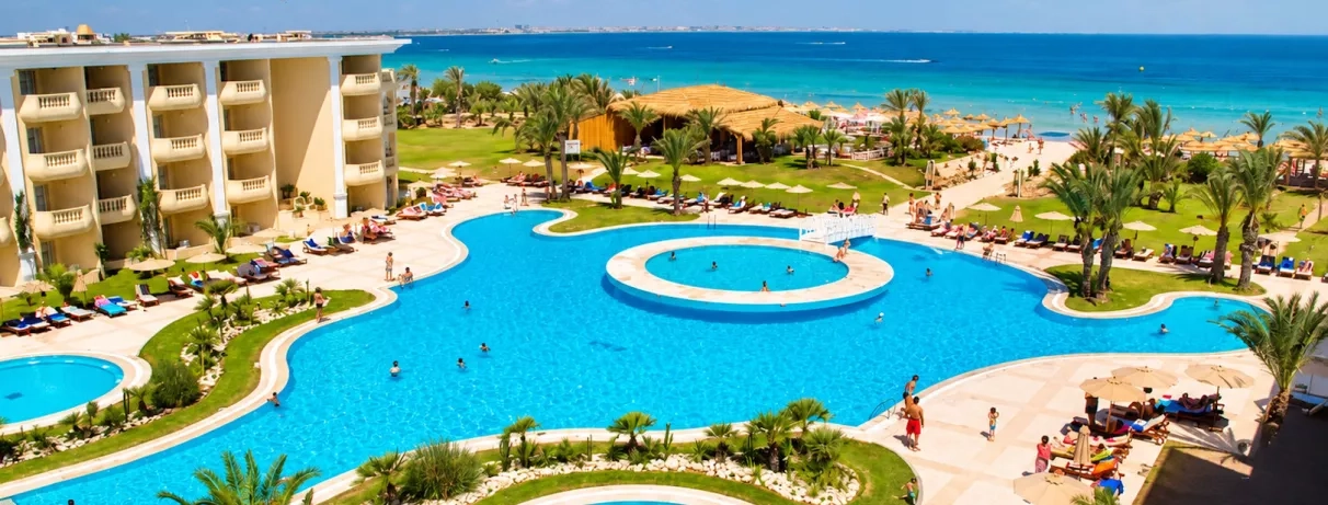 Grande piscine extérieure bleue et jardins palmiers de l'hôtel Royal Thalassa à Monastir, Tunisie.