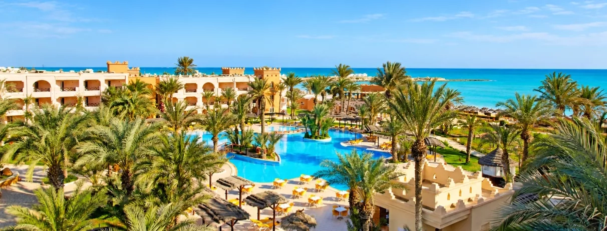Vue panoramique sur les jardins, la piscine bleue et la plage méditerranéenne du complexe touristique Safira Palms Djerba.
