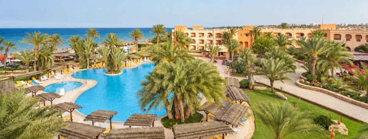 Vue aérienne du jardin, des transats, des palmiers, de la piscine et de la mer méditerranéenne de l'hôtel Safira Palms Djerba.