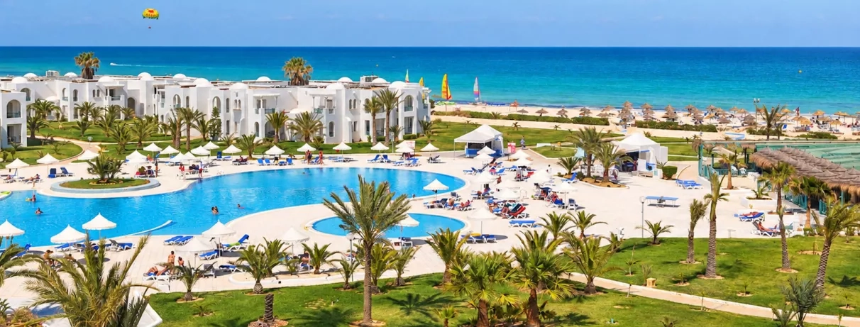 Jardin luxuriant et piscines du complexe hôtelier en bord de mer Méditerranée pour des vacances en Tunisie.