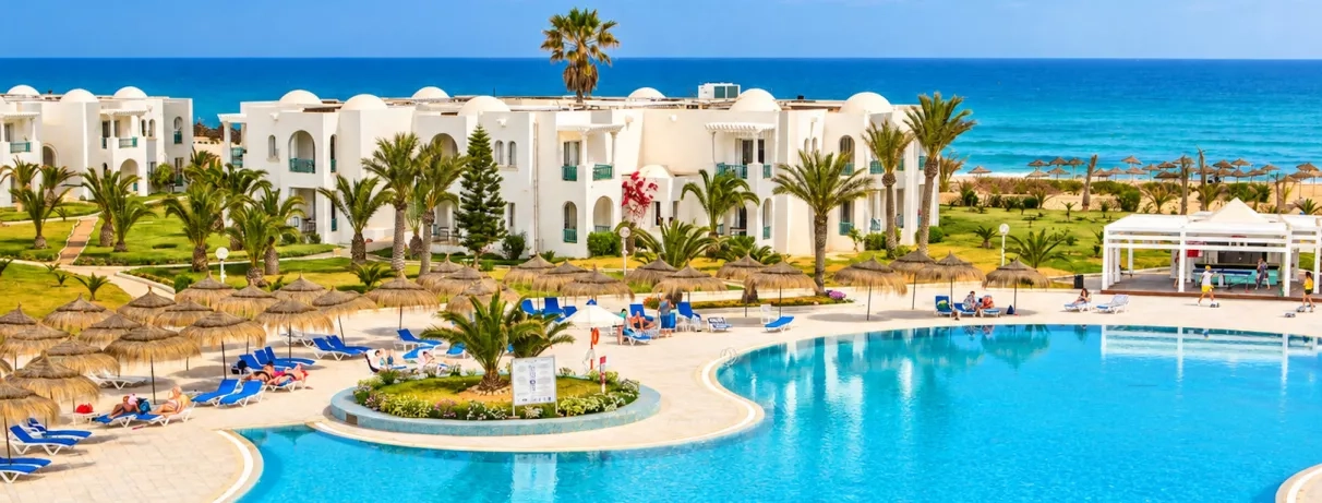 Jardin luxuriant et piscines du complexe hôtelier en bord de mer Méditerranée pour des vacances en Tunisie.