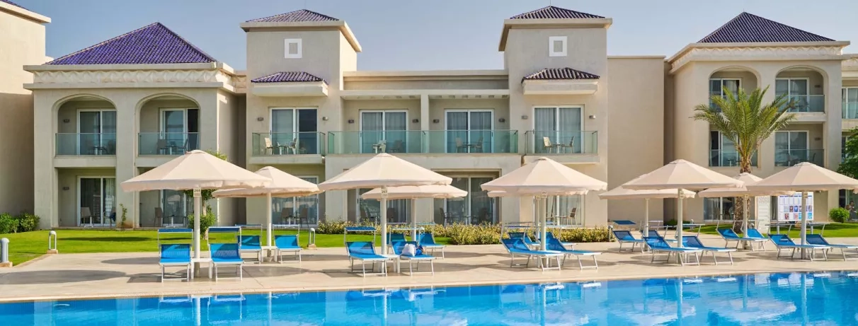 piscine avec transats, hôtel bâtiment avec un étage, lampadaires, plantes, rampe fauteuil roulant et poussettes