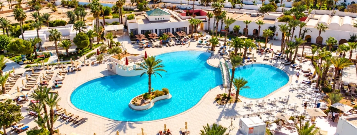 Une vue d'ensemble de l'hôtel, entre piscine à débordement, jardins luxuriants et plage privée, en bordure de mer.