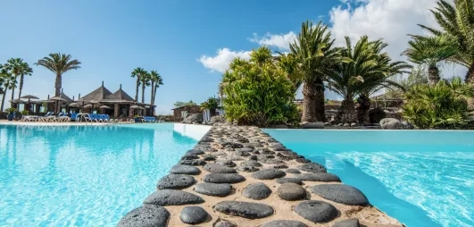 Un gros plan sur une séparation en pierre entre deux sections de la piscine, offrant une vue vers les jardins.