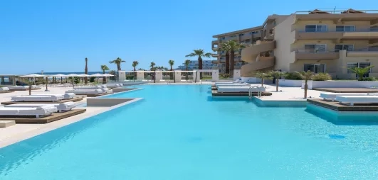 Grande piscine de l'hôtel, bâtiment, transats, parasol, ciel bleu