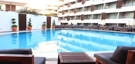 Vue piscine bâtiment de l'hôtel, terrasse, transats