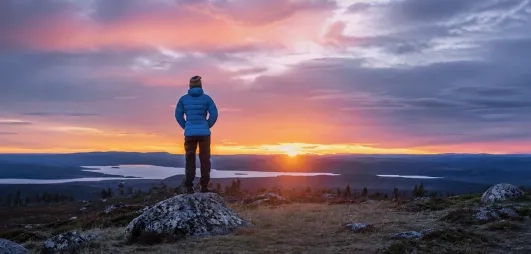 homme contemplant le soleil de minuit à levi en laponie en été 