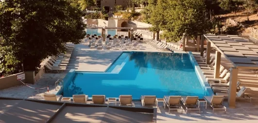 Vue de la piscine extérieur de l'hôtel au milieu du jardin.
