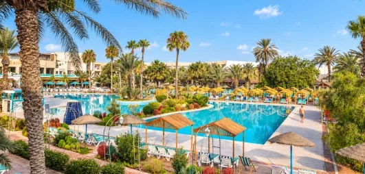 Grande piscine extérieure avec transats et palmiers à l'hôtel tout inclus Welcome Meridiana Djerba