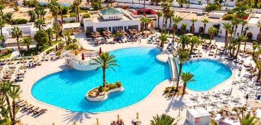 Une vue d'ensemble de l'hôtel, entre piscine à débordement, jardins luxuriants et plage privée, en bordure de mer.