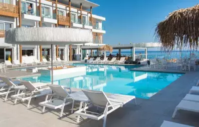 piscine avec transats, parasols, pieds dans l'eau, hôtel avec balcons couleur bois