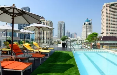 Un rooftop moderne avec piscine, pelouse et transats offrant une vue panoramique sur la ville.