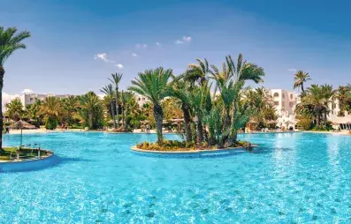 Vaste piscine turquoise entourée de palmiers et d'architecture traditionnelle à Djerba pour des vacances de détente.