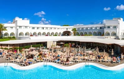 Une vue panoramique d'une grande piscine, bordée de transats devant l'hôtel.