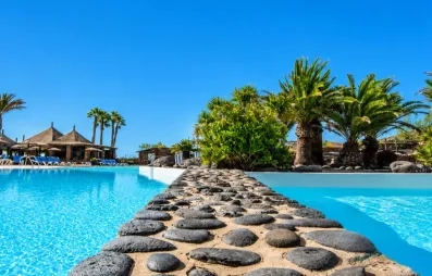 Un gros plan sur une séparation en pierre entre deux sections de la piscine, offrant une vue vers les jardins.