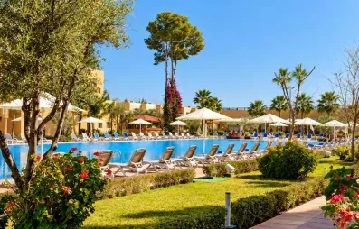 vue générale sur la partie piscine de l'hôtel avec les transats tout autour et une partie jardin