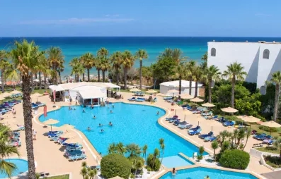 Vue aérienne de la grande piscine extérieure du Mondi Club Thalassa Mahdia entourée de palmiers avec la mer Méditerranée en arrière-plan à Mahdia en Tunisie.