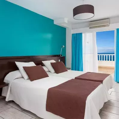 Une chambre avec deux lits simples, avec un balcon privé offrant une vue imprenable sur l'océan.