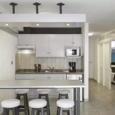 Une cuisine contemporaine et épurée, tout en blanc et gris, équipée d'un bar avec des tabourets design.