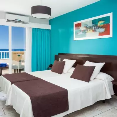 Une chambre montrant la climatisation au-dessus de la terrasse et une décoration murale colorée.