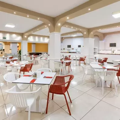 Une vaste salle de restaurant lumineuse aux tons clairs, prête à accueillir les convives pour le repas.