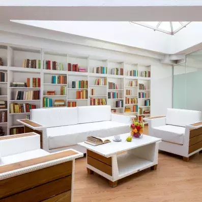 Un salon de lecture lumineux et moderne doté de grands canapés blancs et d'une bibliothèque.