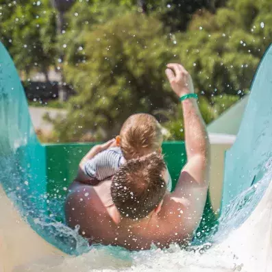 un homme et un enfant glissent d'un toboggan aquatique