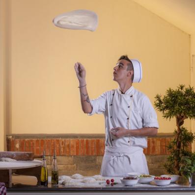 cuisinier faisant sauter une pâte à pizza