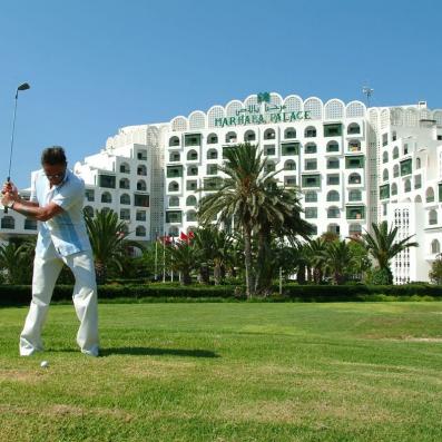 homme jouant au golf devant hôtel