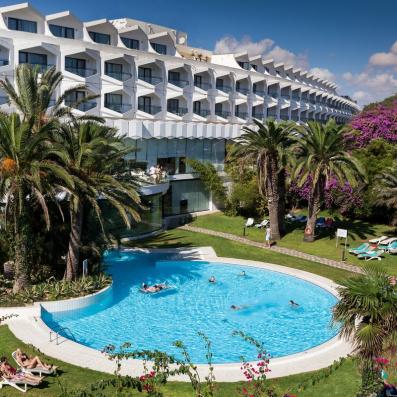 piscine avec palmiers et hôtel derrière