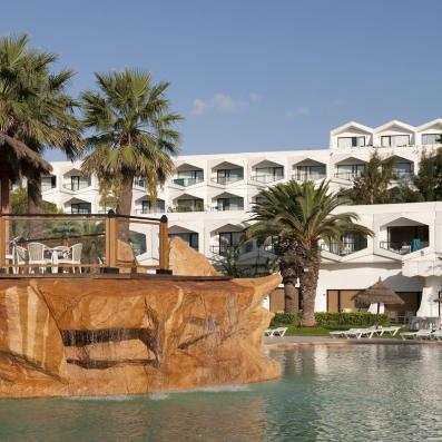piscine avec palmiers et hôtel derrière