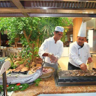 2 cuisiniers faisant griller du poisson