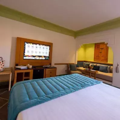 chambre avec lit double et petit plaid en bleu avec télévision et petit salon