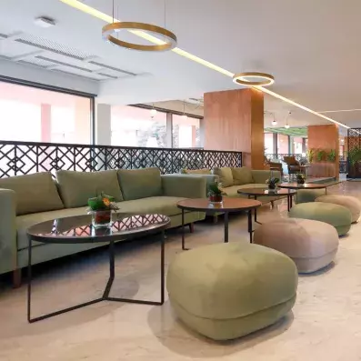 hall d'entrée décoré avec des chaises en rose, vert et gris et des tables basses et des plantes au milieu