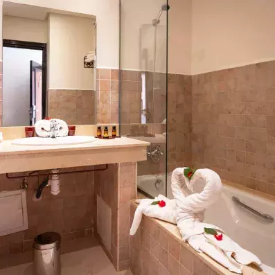 salle de bain avec lavabo intégré et un miroir juste en dessus et une baignoire avec vitre et des serviettes