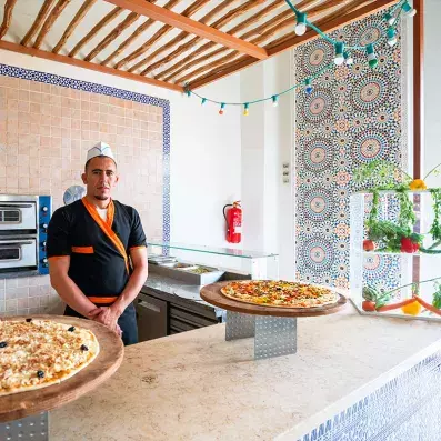 cuisinier au restaurant de l'hôtel avec des pizzas sur le buffet