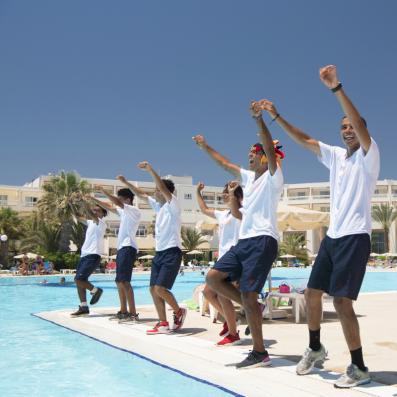 animateurs faisant la danse du village devant piscine