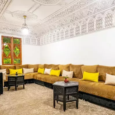 Salon jaune moutarde marocain traditionnel avec un toit sculpté d'un style orientale
