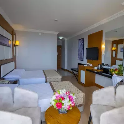 chambre avec lits de profil et tables basse et chaises avec un bouquet de fleur