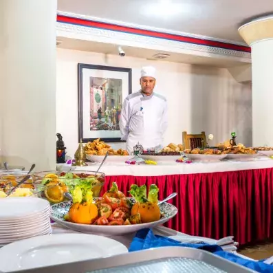 cuisinier de l'hôtel derrière le buffet au restaurant avec des plats chauds et des fruits 