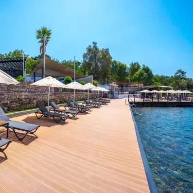 transats et parasols sur un ponton au-dessus de la mer avec une échelle pour y accéder