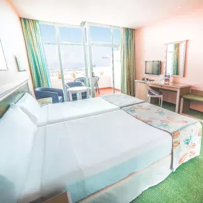 chambre avec deux lits simples télévision et un balcon