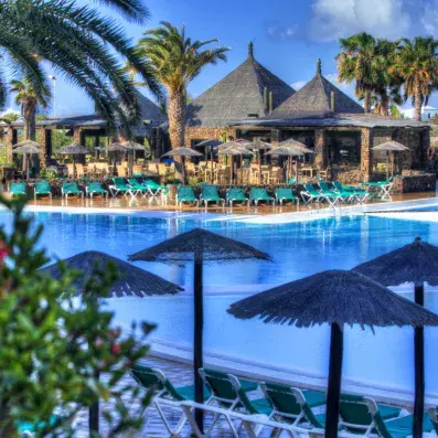 piscine turquoise avec palmiers et parasols en chaume